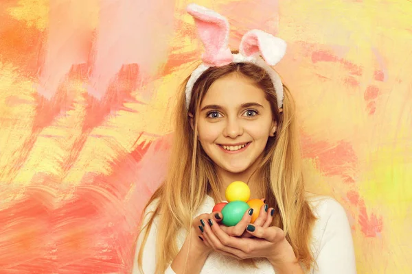 Feliz chica de Pascua en orejas de conejo con coloridos huevos pintados — Foto de Stock