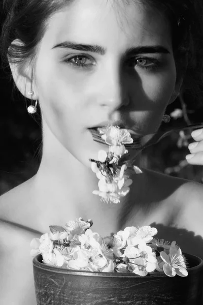 Mulher comendo pétalas de flor de cereja com garfo metálico — Fotografia de Stock