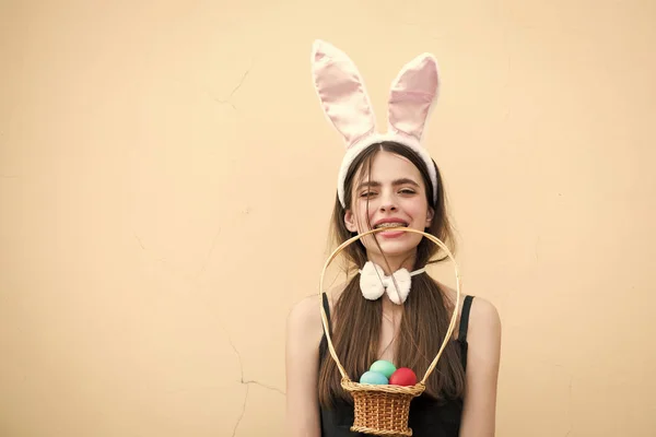 Easter girl holding wicker basket with eggs in teeth — Stock Photo, Image