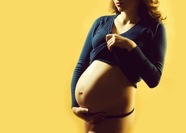 Jolie femme enceinte avec ventre rond nu sur fond jaune — Photo