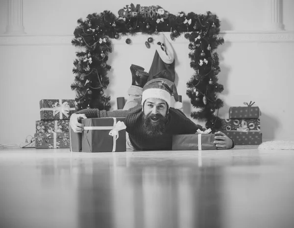 Vánoční muž v klobouku santa držet krabičce u krbu — Stock fotografie