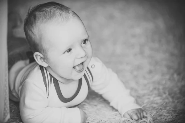 Bebé recién nacido con ojos azules sonríe en el suelo en casa —  Fotos de Stock