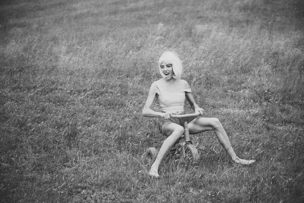 Mulher feliz jogar na bicicleta de brinquedo no verão . — Fotografia de Stock