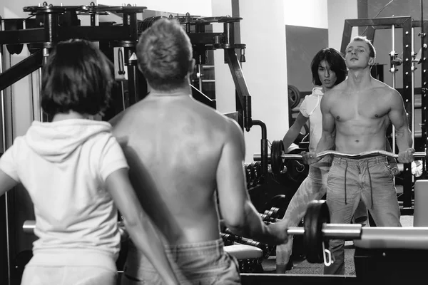 Muscular man and sexy girl at gym trainer with barbell — Stock Photo, Image