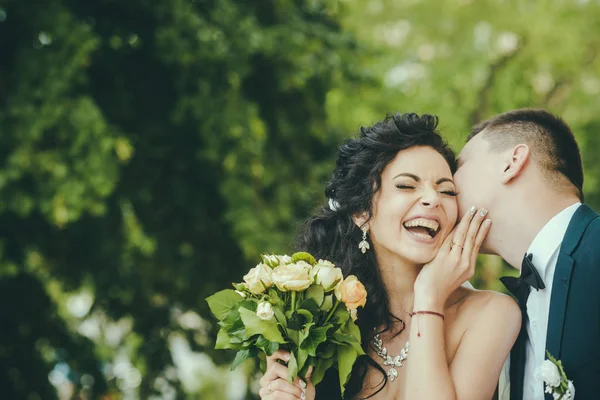 Pareja enamorada besándose y sonriendo el día de la boda. Pareja enamorada en verano al aire libre — Foto de Stock