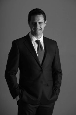 Elleri ceplerinde mavi elbiseli olan gülümseyerek mutlu bir adam