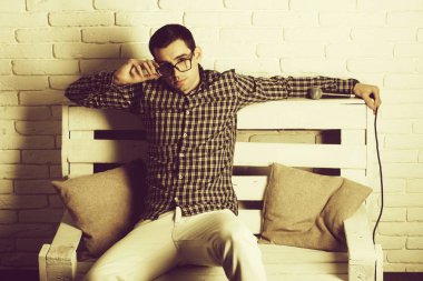 adam gözlük ve mikrofon ile bankta kareli gömlek