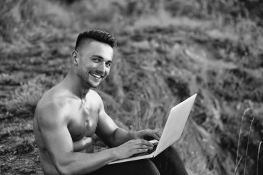 Dizüstü bilgisayar açık ile gülümseyen kaslı adam