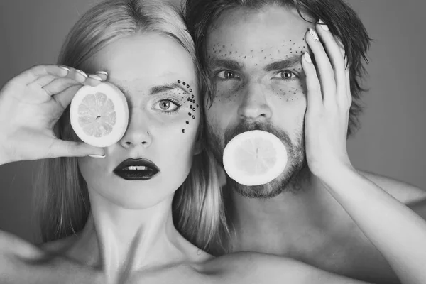 man and girl with makeup hold lemon