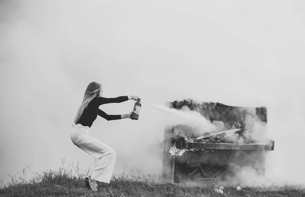 Sexy žena s dlouhými vlasy na piano v ohni, Halloween. Hudební styl a umění. Oheň a kouř na grunge nástroj. Hašení požáru dívka s hasicí přístroj. Hořící klavír a móda žena na rockový koncert — Stock fotografie