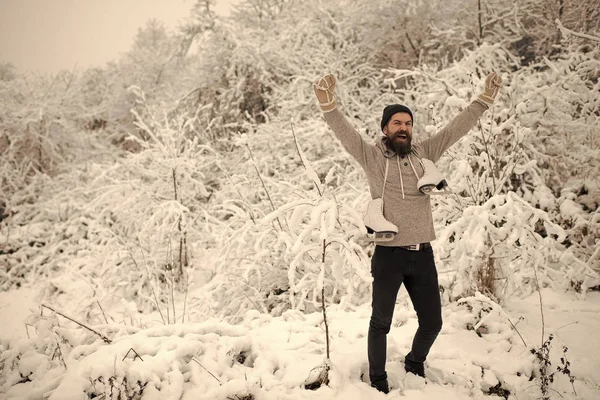 Homem feliz barbudo segurar patins na floresta de inverno nevado, natal — Fotografia de Stock