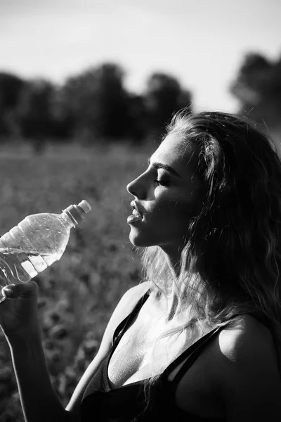 ケシのフィールドで女の子でペットボトルの水します。 — ストック写真