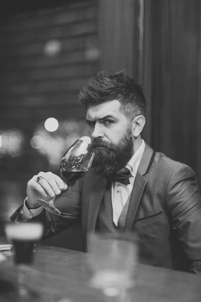 Young man holding a glass with red wine, bar on background — Stock Photo, Image