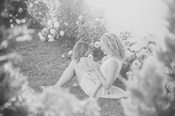 妇女与女孩在绽放的玫瑰色花 — 图库照片