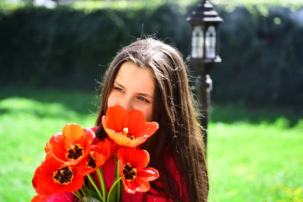 春祭り。花の球根花と少女。花の花束を持つ少女です。春の日の赤いチューリップの花とかわいい女の子の子。8 月や女性の日を祝います。春の開花 — ストック写真