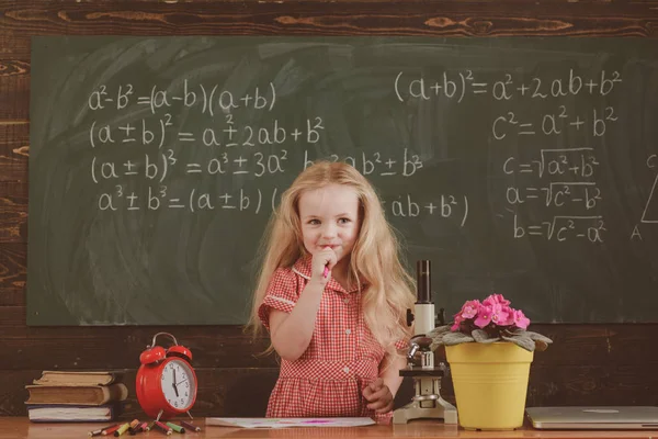 Маленькая девочка думает о математической проблеме в классе. Школьники решают проблему в школе — стоковое фото