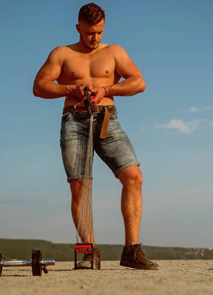 Entrenamiento muscular y construcción. El deportista construye músculo con banda de resistencia. Hombre musculoso en cuerpo completo en el cielo azul. Un hombre con seis músculos. Quemar la grasa corporal antes de que dañe su salud —  Fotos de Stock