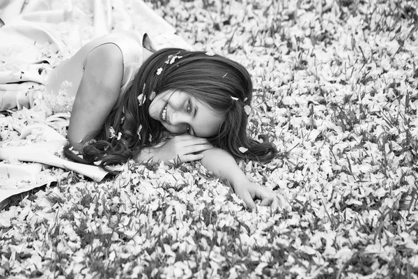 Menina na grama verde com pétalas — Fotografia de Stock