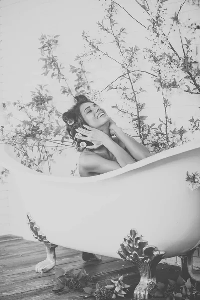 Mujer con rulos en el pelo sentarse en el baño, cuidado del cuerpo . — Foto de Stock