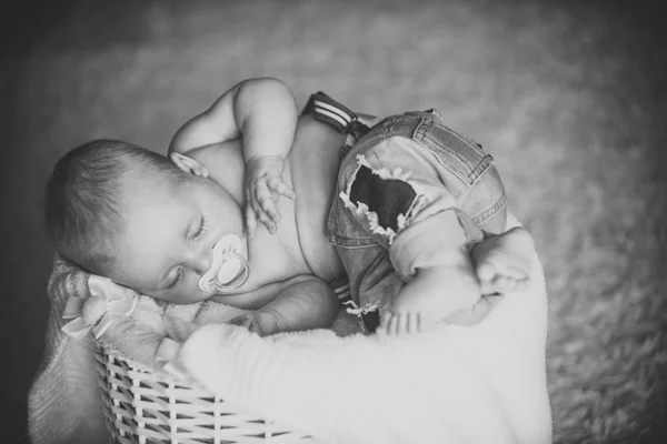 Nyfött barn i jeans sova i korgen på golvet — Stockfoto