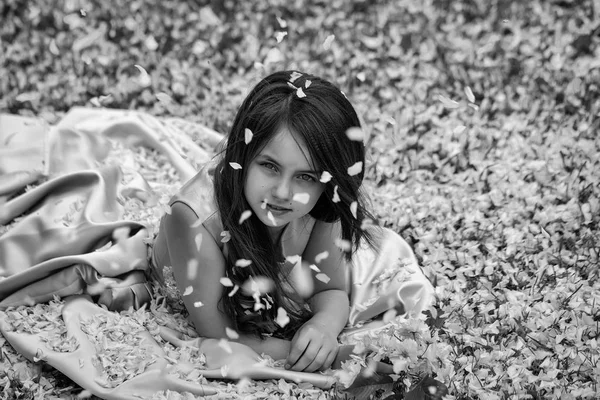 Little girl on green grass with petals — Stock Photo, Image