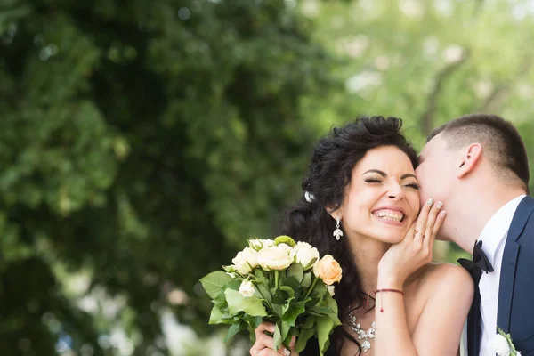 Kersverse man kus gelukkige vrouw met boeket. Jonggehuwde paar glimlach op zomer buiten — Stockfoto