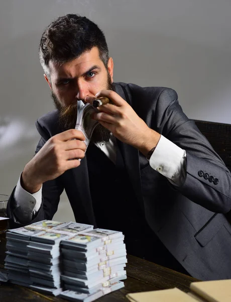 L'argent et le pouvoir. Affaires et finances. L'homme barbu compte les dollars en fumant du cigare. Un homme d'affaires prospère détient de l'argent comptant. Homme riche avec barbe en tenue de cérémonie. Faire croître une entreprise — Photo