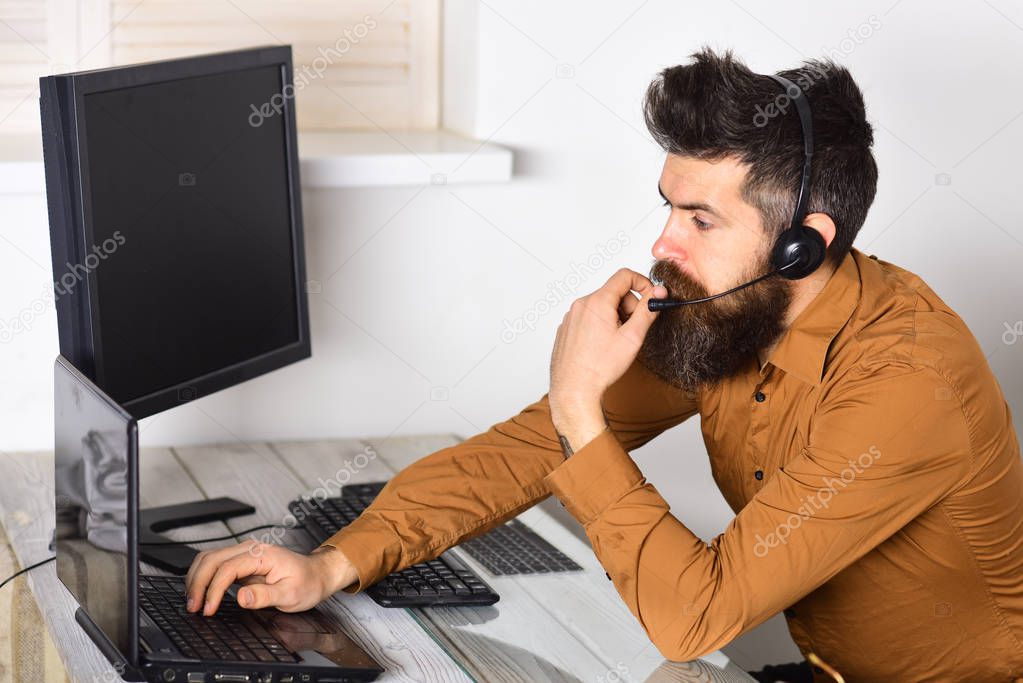 Operator online. Bearded man working in office. Call center operator at work. Man with long beard and headphones. Bearded company representative with laptop. Responding the calls from customers