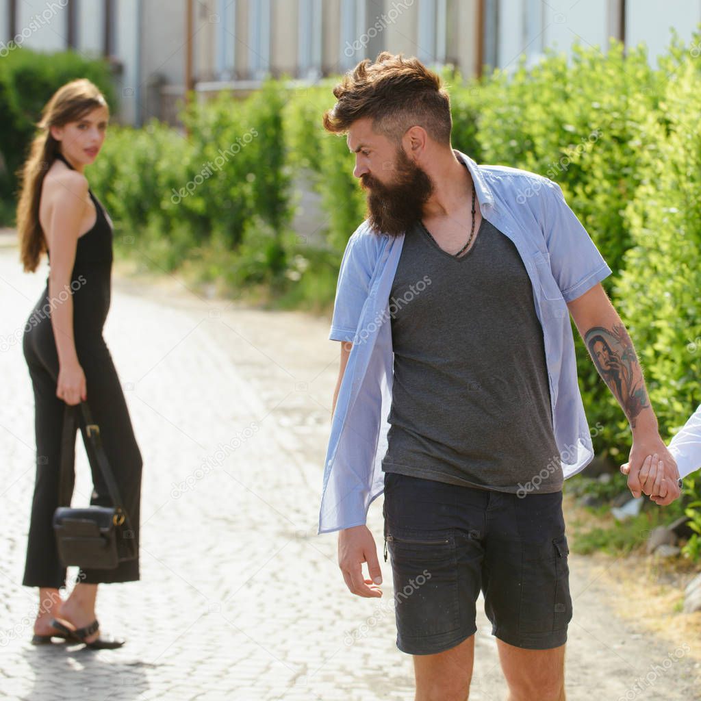 Feeling flirtatious. Bearded man and cute woman walk on street. Hipster look back at pretty woman. Couple in love on summer day. Enjoying the flirtation. Romantic date and dating. Little flirtation