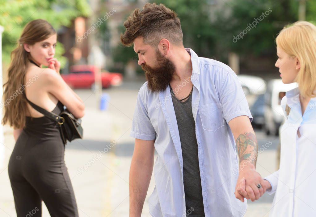 Flirting in the street. Love triangle and threesome. Man cheating his girlfriend. Bearded man looking at other girl. Hipster choosing between two women. Betrayal and infidelity. Unfaithful love