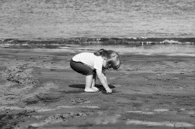 Şirin bebek çocuk kum ile kumlu plaj üzerinde çalış.