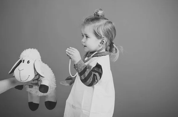 Boy play veterinarian with toy sheep in mothers hand