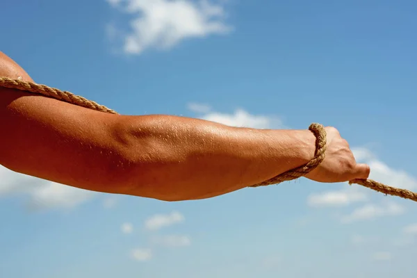 Having strength in his muscles. Male muscular hand pulling rope. Strong arm tugging rope. Test of muscular strength. Sport training. Physical strength and muscular power. Sport and fitness