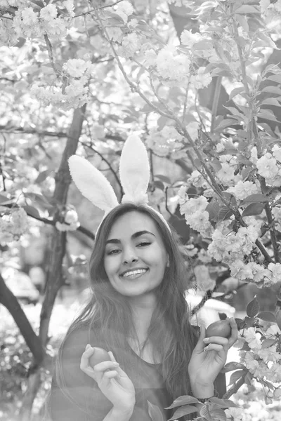 Gelukkig meisje met bunny oren glimlachend met gekleurde eieren, sakura — Stockfoto