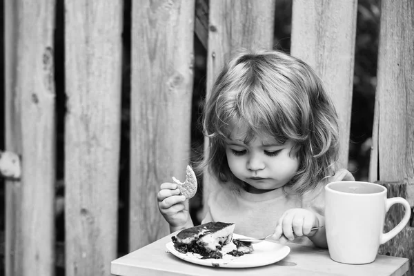 Small boy eating pie near wooden fence — Stock Photo, Image