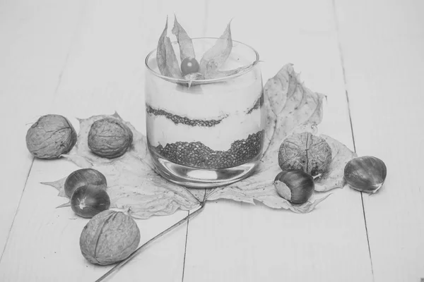 Room met bloem in glas op esdoornblad met noten — Stockfoto