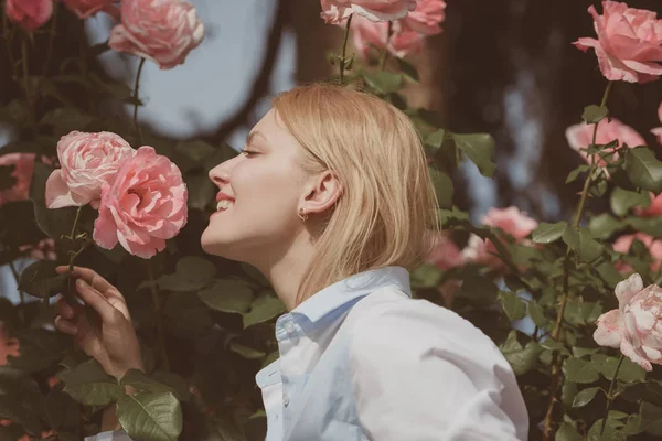 Tão terno como uma flor. A mulher jovem no momento da floração aumentou arbusto. Mulher bonita cheiro rosa flores no jardim de verão. Mulher adorável desfrutar flor flor. Flor de flor de verão — Fotografia de Stock