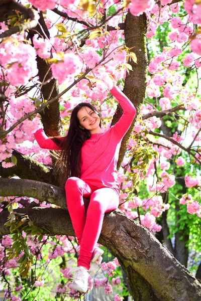 Onun bireysel moda anlayışı. Çiçekli ağaç üzerinde şık genç bayan. Bahar moda giyim. Bahar bahçe moda giyim, küçük kız. Moda bakmak güzel kızla