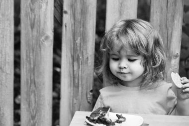 küçük çocuk ahşap çit yakınındaki pasta yemek