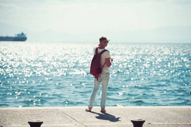 adam gezgin uzakta denizde seyir su sırt çantası ile. seyahat ve yolculuk tutkusu kavramı. yaz tatili ve maceraları. Genç adam deniz gezisi gidiyor. futute hayat kavramı