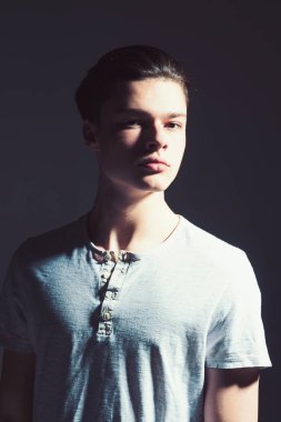 Maço şık uzun saç kesimi ile. Erkeklik kavramı. Pürüzsüz bir cilt ve yüz, kopya alanı üzerinde gölgeler olan adam. Adam kendine güvenen yüzüne ışık gömlek, siyah arka plan üzerinde.