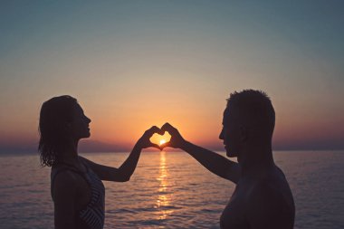 kadın ve erkek deniz suyu günbatımı içinde boyuyla kalp ile. Yaz tatil ve seyahat etmek tatil. Aile ve Sevgililer günü. Aşık çift sunrise plajda dinlenebilir. Aşk ilişkiler yaz zevk çift.