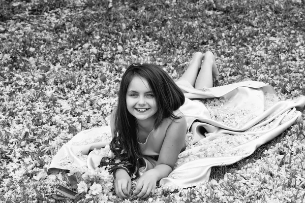 Petite fille sur herbe verte avec des pétales — Photo