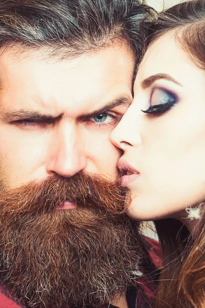 Чувственная женщина целует бородатого мужчину, милая. Женщина с макияжем кожи и хипстер с длинной бородой. Пара влюбленных и семейная концепция. Салон красоты и парикмахерская. Концепция ухода за кожей и волосами — стоковое фото