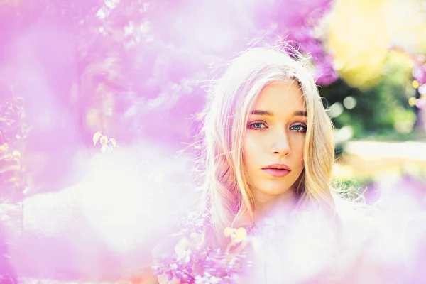 Young woman enjoy flowers in garden, defocused, close up. Girl on dreamy face, tender blonde near violet flowers of judas tree, nature background. Lady in park on spring day. Spring bloom concept. — Stock Photo, Image