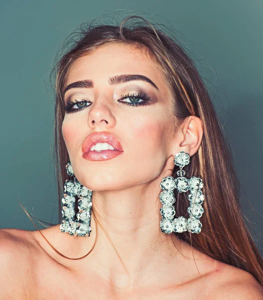 Glamour jewelry of luxury big earrings. Girl with sexy lips makeup. Fashion model with trendy look. Beauty on party. My favorite earrings. Sexy woman with fashionable makeup on face