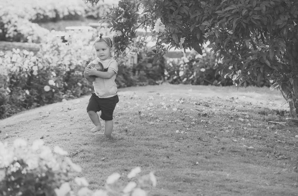 Kid in tuin met bloeiende bloemen — Stockfoto