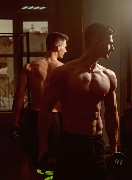 Man met torso, gespierde macho en zijn reflectie in de spiegel achtergrond. Sport en fitness concept. Sportman, atleet met spieren ziet er aantrekkelijk uit. Man met naakte torso in sportschool genieten van zijn sportieve levensstijl. — Stockfoto