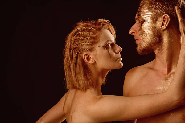 Эротические игры влюблённых пар. Золотой спа и лечение кожи. Отношения между мужчиной и женщиной. Золотая маска и красота коллагена. 24K Gold. Сексуальная пара с золотым макияжем, изолированная на черном
