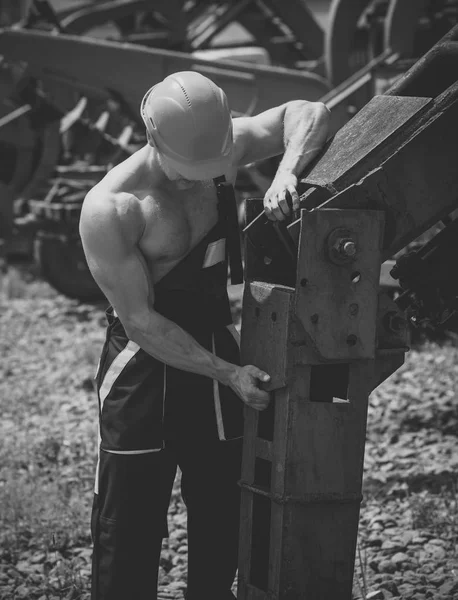 Constructor muscular en sombrero duro lleva overoles . —  Fotos de Stock